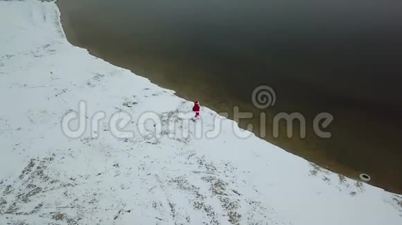 圣诞老人站在湖的雪岸上带着一个礼品袋北极的圣诞老人顶部视图视频的预览图