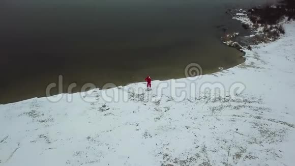 圣诞老人站在湖的雪岸上带着一个礼品袋北极的圣诞老人顶部视图视频的预览图
