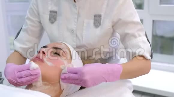 美容师戴着手套从女人脸上擦拭面具特写肖像视频的预览图