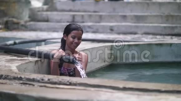 漂亮的亚洲女孩坐在游泳池里享受着流动的水视频的预览图