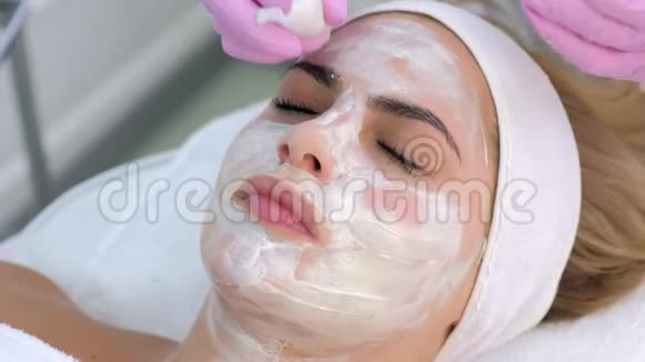 美容师戴着手套从女人脸上擦拭面具特写肖像视频的预览图