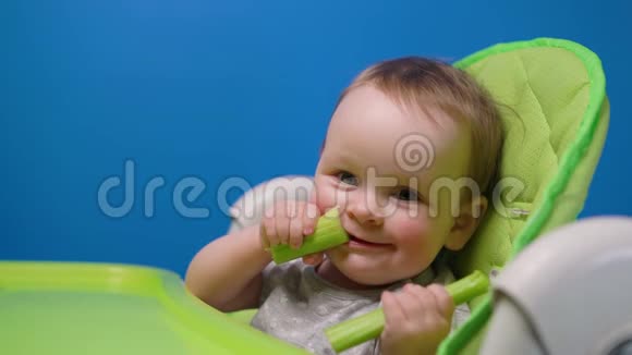 有趣的宝宝吃绿色的新鲜芹菜看着镜头视频的预览图