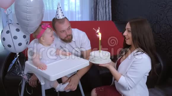 妈妈在一岁的女婴生日聚会上给女儿一个带蜡烛的蛋糕视频的预览图