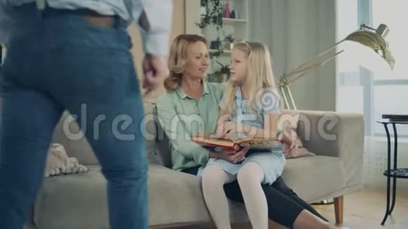 带着小女孩和祖父母一起读书的客厅视频的预览图