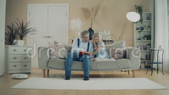 爷爷和一个小女孩正在沙发上看书视频的预览图