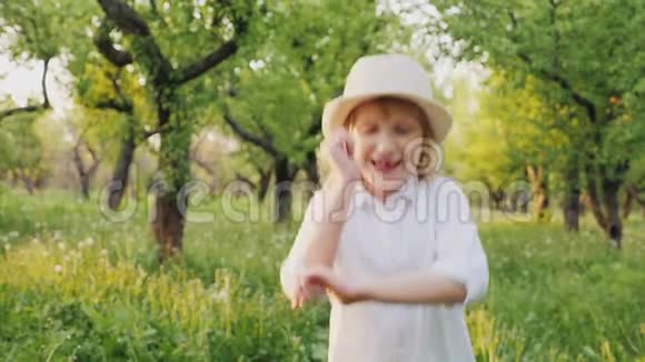 戴着帽子的无忧无虑的金发女孩穿过苹果园视频的预览图
