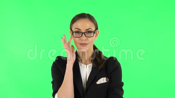 一幅穿着布松西装的黑发女孩戴着眼镜扬起眉毛微笑着向绿色屏幕画像视频的预览图