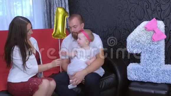 在家里举行的第一次生日聚会上父母和女婴的家庭肖像视频的预览图