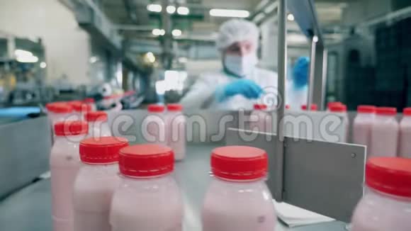 一个女人从乳品厂的传送带上拿瓶子视频的预览图
