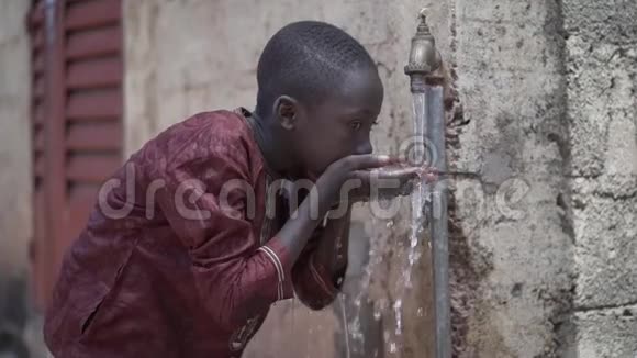 英俊的非洲小男孩从家里的水龙头里喝着安全的可饮用的干净的水视频的预览图