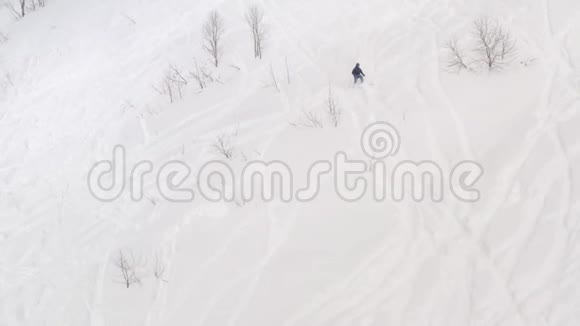 滑雪者在冬季度假胜地的雪坡上自由地滑雪空中观景滑雪者在w山坡上驾驶下降视频的预览图