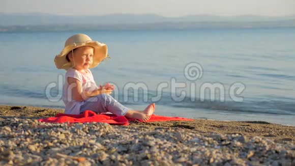 带有婴儿眼睛的海景小女孩坐在海岸上看海景暑假背景童年视频的预览图