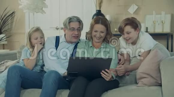 奶奶和爷爷一起玩孙子孙女和笔记本电脑视频的预览图