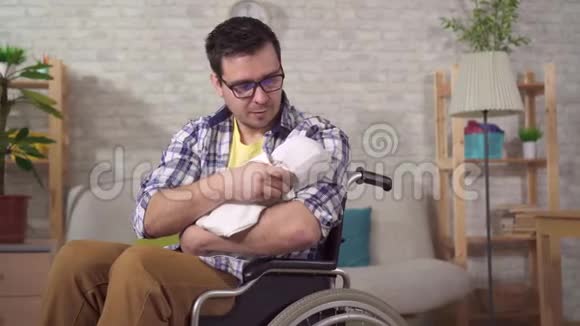 一个年轻的父亲是一个坐轮椅的残疾人手里拿着一个新生儿视频的预览图