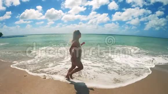 美丽的女人正慢慢地沿着海滩奔跑视频的预览图