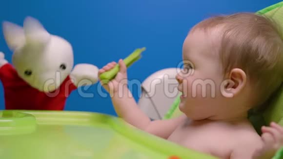 可爱的孩子宝宝吃绿色的新鲜芹菜棒玩兔子娃娃视频的预览图
