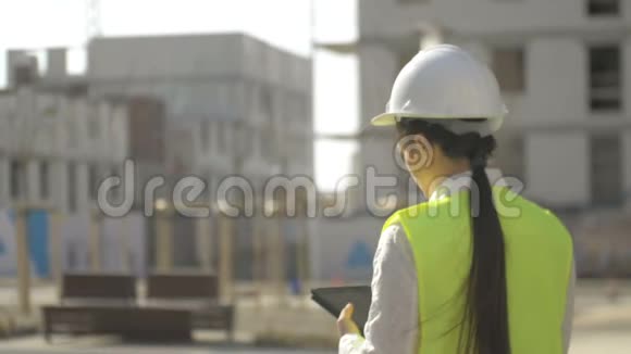 年轻的建筑女性在平板电脑上做条目后景在建物的背景下视频的预览图