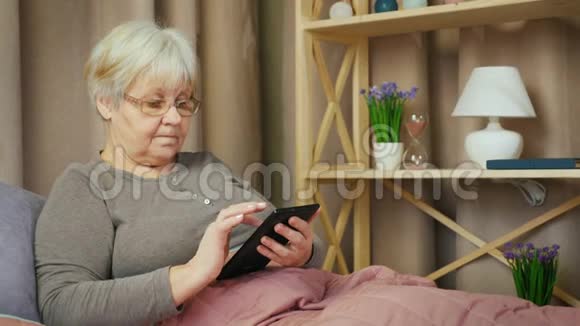 老年妇女在房间里放松使用平板电脑视频的预览图