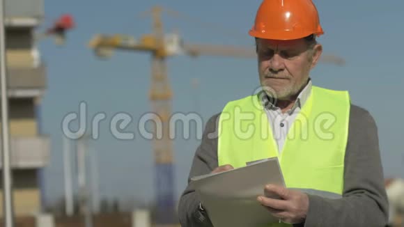 一位年长建筑工人的肖像在建物的背景下有东西在写视频的预览图