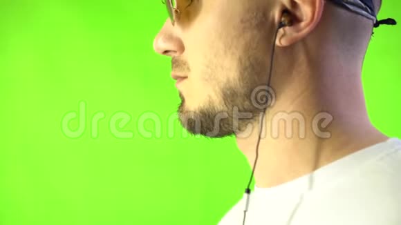 时尚的年轻人戴着时髦的眼镜戴着听耳机音乐的手帕铬基背景视频的预览图