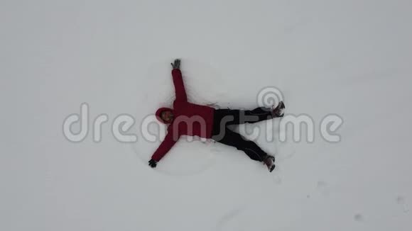 鸟瞰一个女人躺在雪地里双手拉起天使的翅膀视频的预览图