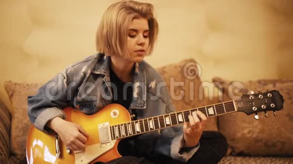 女孩弹吉他在沙发上唱歌女人在室内创作音乐艺术家在吉他上表演一位音乐家视频的预览图