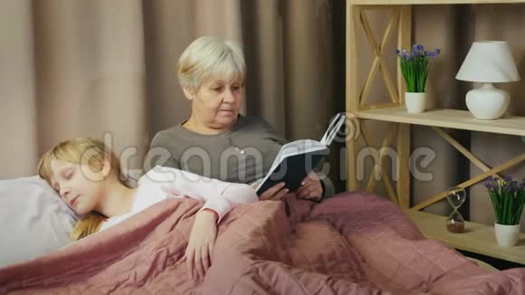 一位老妇人给一个在附近睡着的孩子读童话视频的预览图