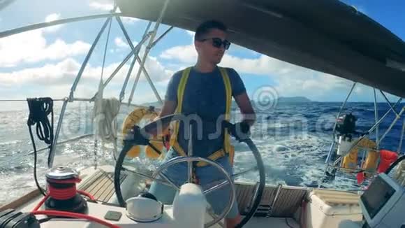 驾驶帆船的人的正面视图由一个年轻人控制的海洋帆船视频的预览图