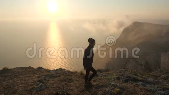 一位身穿班达纳服装的运动型旅游女孩沿着高崖的边缘走着从快乐中将手臂伸展到一边视频的预览图