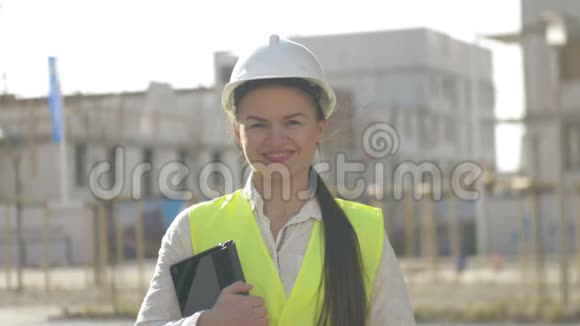 女建筑工人在施工现场穿着防护服年轻的女人拿着平板电脑微笑视频的预览图