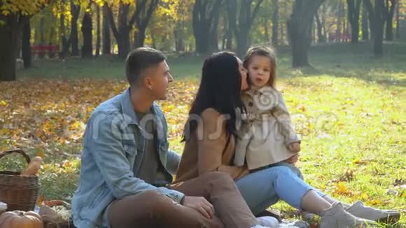 母亲和父亲带着女儿在户外玩得很开心秋天公园野餐视频的预览图