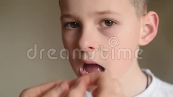 母亲松开并试图用牙线拔出一颗婴儿牙齿给一个小男孩视频的预览图