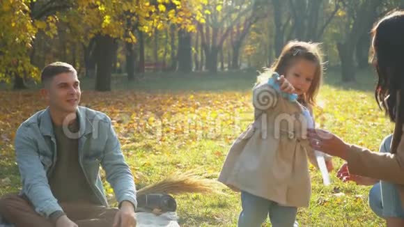 母亲和父亲带着女儿和狗在户外玩得很开心秋天公园野餐视频的预览图