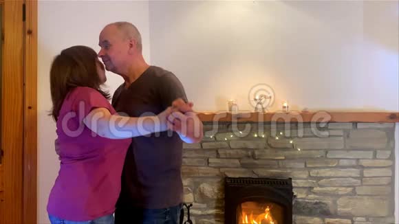 夫妻中年男女在燃烧的壁炉边跳舞微笑爱的概念家庭关系好心情视频的预览图