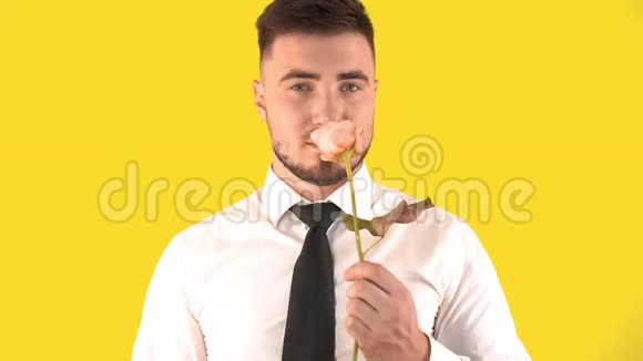 穿着白色衬衫的帅哥和在黄色背景上系着玫瑰嗅丝视频的预览图