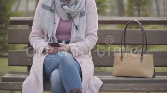 男性白种人的手从无法辨认的女人的钱包中偷钱包用智能手机吸收成年女士输钱视频的预览图