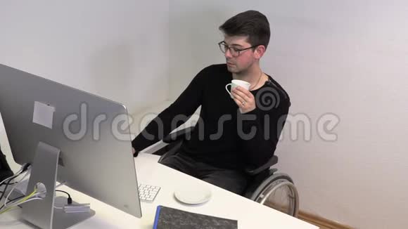 办公室工作人员坐在轮椅上黑发女人在靠近电脑的工作场所喝咖啡动作迟缓视频的预览图