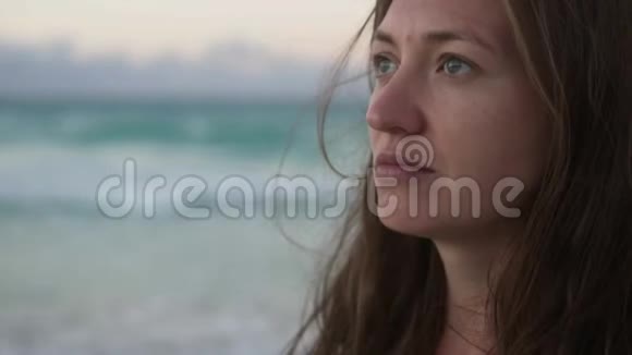在被冲刷的海洋背景下一个没有化妆的美丽女人的特写视频的预览图