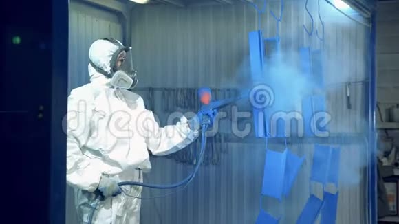 一名工人正在油漆工厂的工厂里把蓝色油漆喷到金属件上视频的预览图