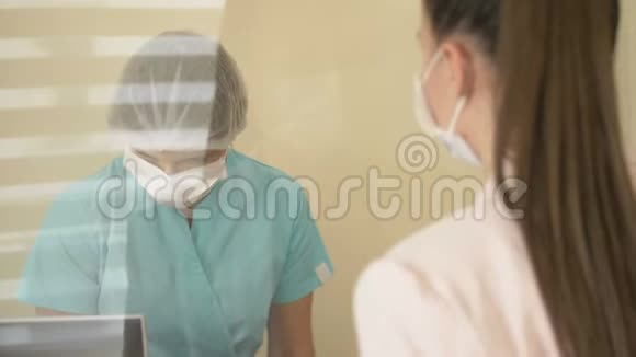 在医院候诊室值班护士正在与病人交谈护士和病人戴医用口罩视频的预览图