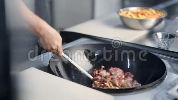 特写厨师手把炒肉和洋葱混合在煎锅上的沸水4k龙红相机视频的预览图