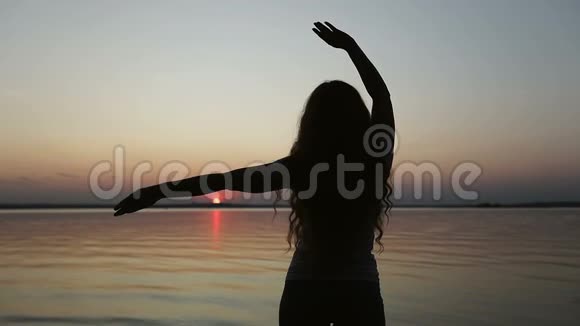 后景一个年轻的女人在日落时跳舞视频的预览图