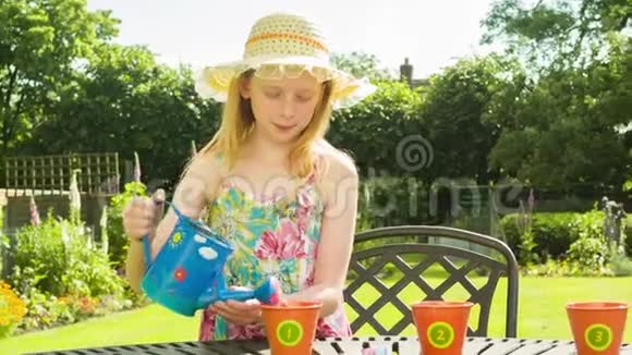 十几岁的白种人女孩在花园里浇花盆视频的预览图
