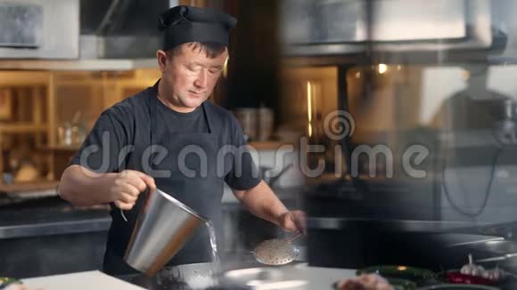 亚洲男厨师在煎锅上烹饪食物在烹饪时加水中型摄影机视频的预览图