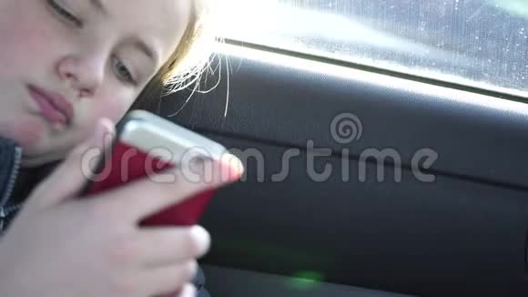 快关门悲伤的女孩在车里无聊地看着智能手机视频的预览图
