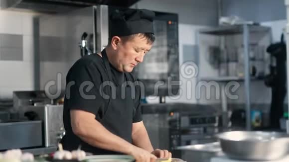 亚洲男厨师在餐厅厨房准备食物切割配料中型摄影机视频的预览图