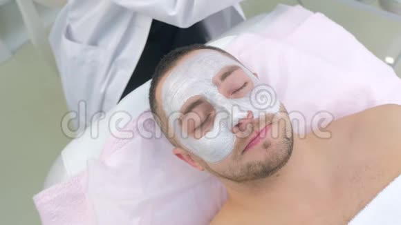 美容师用人造手套擦拭人脸保湿面膜视频的预览图