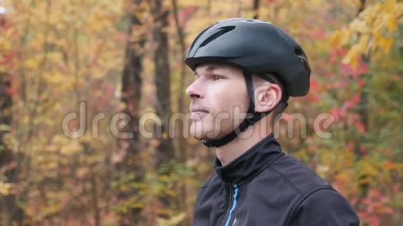 在秋天公园骑自行车锻炼前精力充沛的年轻男性自行车运动员戴上运动眼镜的肖像可爱的白种人视频的预览图