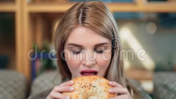 可爱的节食女孩的特写脸咬着新鲜的糕点食物感觉很愉快4k龙红相机视频的预览图