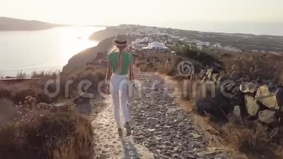 可爱时尚的女孩或穿着白色裤子或牛仔裤行走在希腊的塞托里尼岛视频的预览图